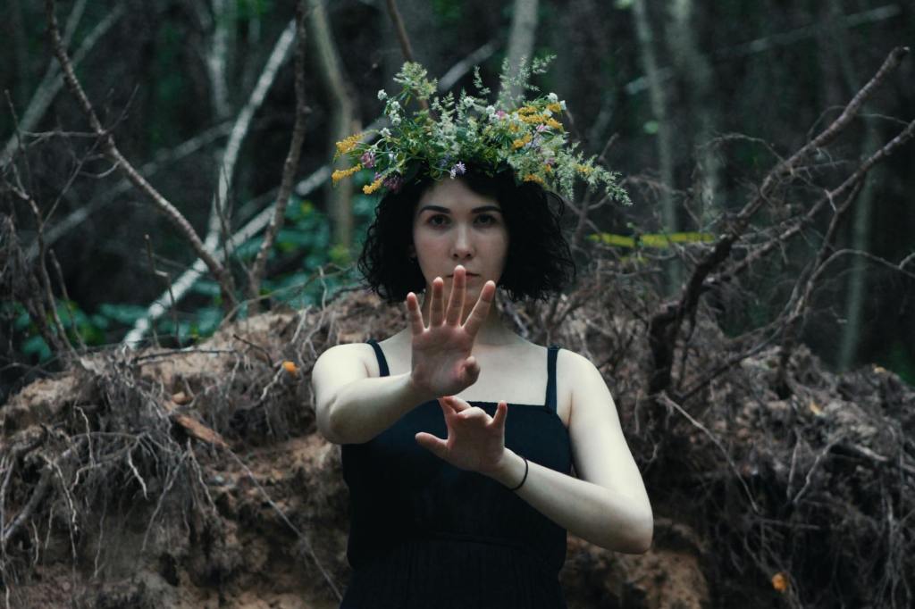 a woman in black spaghetti strap dress posing at the camera