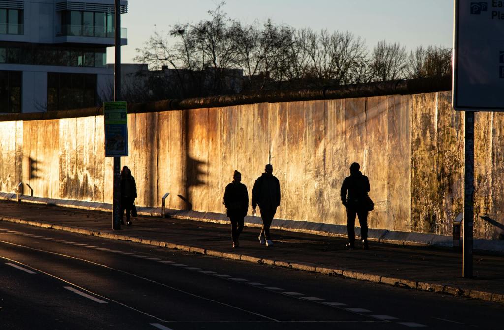 silhouettes walking along a historic wall at sunset
